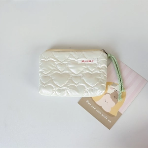 Detail of quilted heart texture on a cream PU leather mini makeup and coin pouch