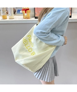 Detail view of cream oversized tote bag with yellow Paris print on female model