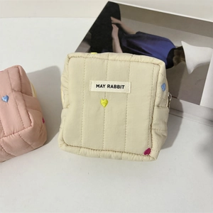 Quilted makeup bag with colorful heart embroidery and top zipper in beige and pink