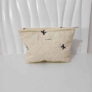 Detail of quilted cotton makeup bag featuring black bow patterns and zipper closure