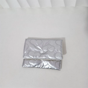 Detail of silver heart-quilted pouch showing the central snap button closure