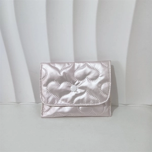 Close-up of pink quilted coin purse featuring heart patterns and a white snap button