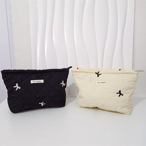 Detail of quilted cosmetic bags in black and cream featuring cute bow embroidery