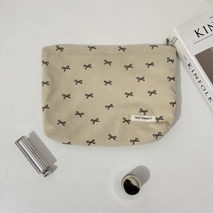Mise à plat de trousse à maquillage en velours côtelé crème avec imprimé nœuds