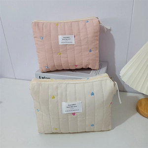 Detailed macro view of quilted makeup bags with colorful heart embroidery and secure zippers