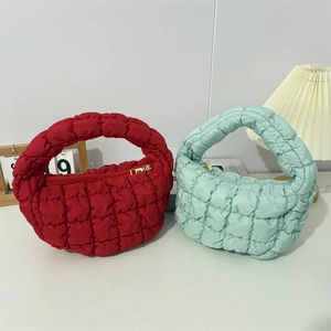 Close-up of red and mint green quilted cloud bags with square texture and gold zipper
