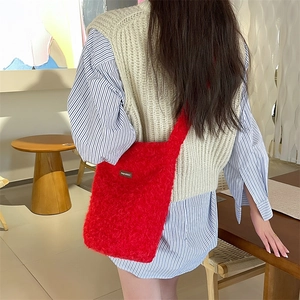 Détail du sac seau en peluche rouge avec petite étiquette de marque en cuir sur texture