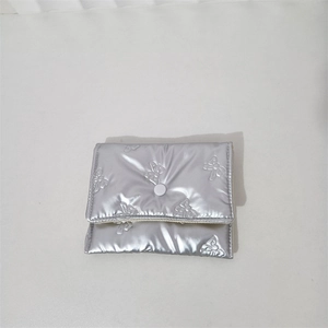 Detail of silver metallic quilted clutch with bow embossing and white snap button closure