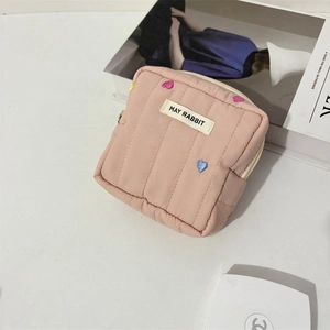 Close-up of pink quilted makeup bag with colorful heart embroidery and May Rabbit label