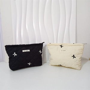Detail of quilted cosmetic bags in black and cream featuring cute bow embroidery