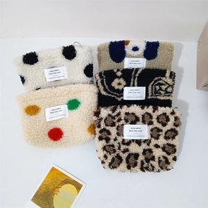 Flat lay of multiple fluffy plush pouches in dot, leopard, and cartoon patterns