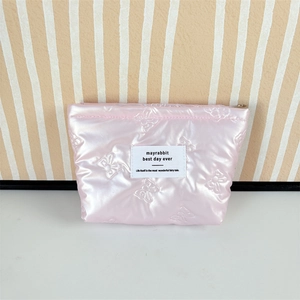 Close-up of pink quilted puffy cosmetic bag with bow embroidery and gold zipper
