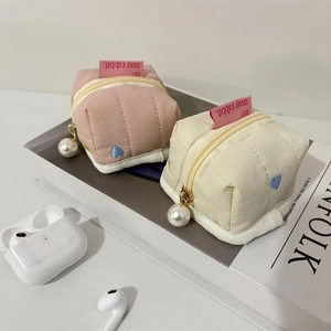 Close-up of quilted fabric mini bags with heart embroidery and pearl zipper charms