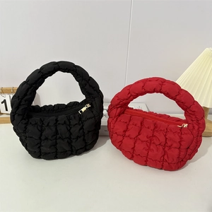 Detail shot of quilted cloud handbags in black and red with gold zipper and puffy texture