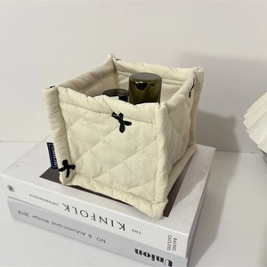 Detailed view of cream quilted storage bin with black bow embroidery and fabric texture