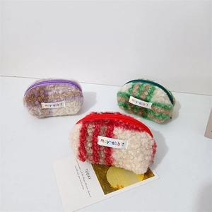Close-up of three checkered plush shell-shaped coin purses in purple, green, and red colors