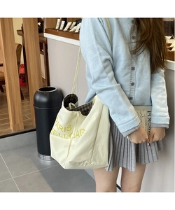 Close-up of cream canvas tote bag with yellow PARIS text and brown plaid lining