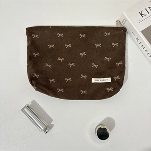 Vue détaillée d'une trousse à maquillage en velours côtelé marron avec motifs de nœuds