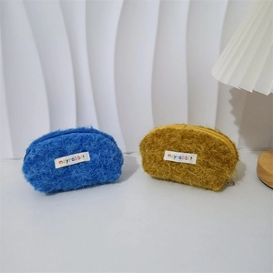 Dettaglio di mini borse porta trucco in peluche blu e giallo con cerniere resistenti