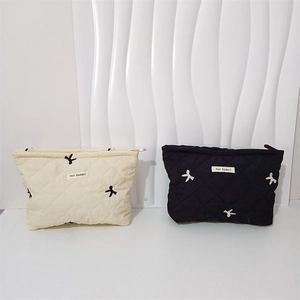 Detail of quilted makeup bags featuring bow embroidery and secure metal zipper closure