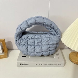 Detail shot of light blue quilted cloud handbag showing soft puffy texture and zipper