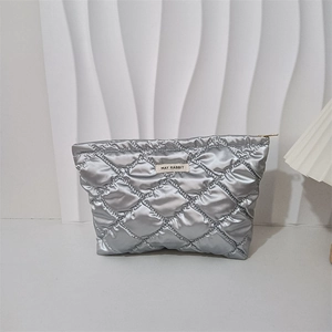 Makro-Detail der silbernen gesteppten PU-Kosmetiktasche mit Metallfinish und Markenetikett