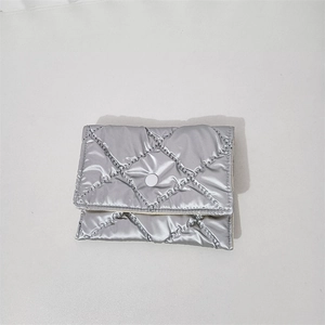 Macro shot of silver quilted pouch with classic diamond stitching and metal snap closure