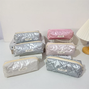 Close-up of heart quilted metallic makeup bags with zip closure and fabric labels
