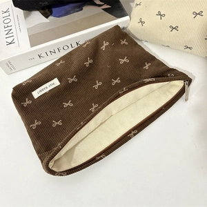 Détail de la pochette en velours côtelé marron à nœuds avec un magazine déco