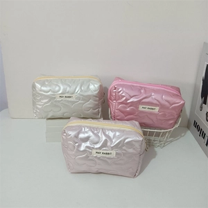Detailed close-up of heart-quilted PU makeup bags with metallic finish and brand label