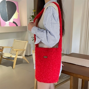 Détail du sac seau en peluche rouge montrant la texture douce et l'étiquette