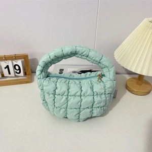 Detailed view of mint green quilted cloud bag with gold zipper and puffer texture