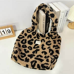 Dettaglio della borsa tote in peluche maculata con etichetta tessuta sulla scrivania