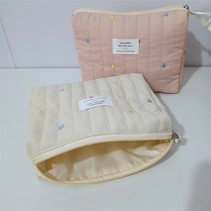 Close-up of quilted cosmetic bags with colorful heart embroidery and secure zipper
