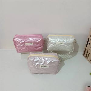 Close-up of quilted cosmetic bags with heart patterns in pink, white, and lilac purple