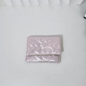 Detail of pink satin mini storage bag featuring heart-shaped quilted pattern and snap button