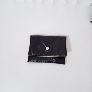 Close-up of black quilted pouch with butterfly embossing and white snap button closure