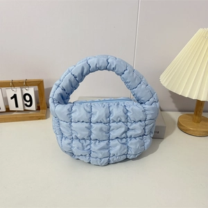 Close-up of light blue quilted puffer bag with soft bubble texture and top zipper detail