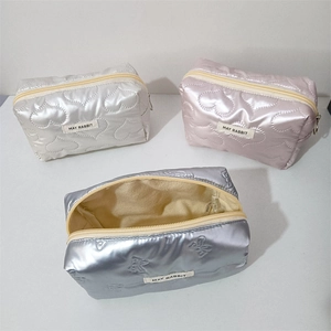 Close-up of three quilted PU cosmetic bags in metallic silver, pink, and blue colors