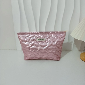 Nahaufnahme der herzförmigen Steppung auf der rosa metallischen Make-up-Tasche