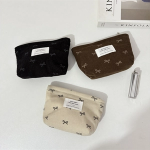 Trois trousses à maquillage en velours côtelé avec nœuds en noir, brun et beige