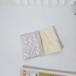 Detailed view of silver quilted storage pouch with heart pattern and white button closure