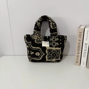 Detail of plush paisley pattern handbag with woven tag on white minimal background