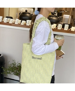 Dettaglio della borsa tote in tela con spalline a volant e motivo a quadretti gialli