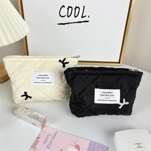 Close-up of quilted cosmetic bags with airplane embroidery and chic fabric labels