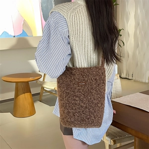 Gros plan du sac seau en peluche marron foncé montrant la texture douce et l'étiquette