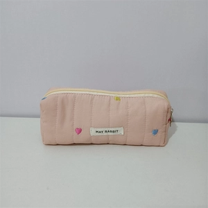 Close-up of quilted makeup bag featuring colorful heart embroidery and MAY RABBIT tag