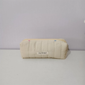 Detailed view of quilted beige pouch with MAY RABBIT label and colorful embroidery