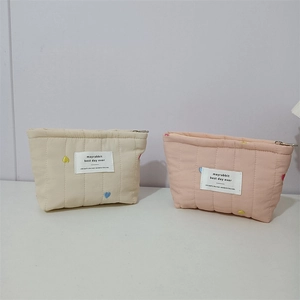 Detailed view of quilted fabric textures with heart embroidery on colorful makeup bags