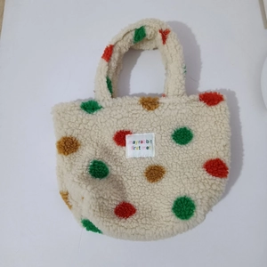 Detail of off-white teddy fleece tote bag with red, green and brown plush polka dots